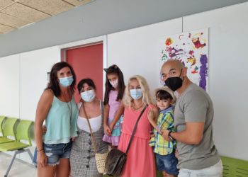Abril Fajardo, de ocho años, con su familia posa ante uno de sus cuadros en el Centro de Salud de Sant Antoni.