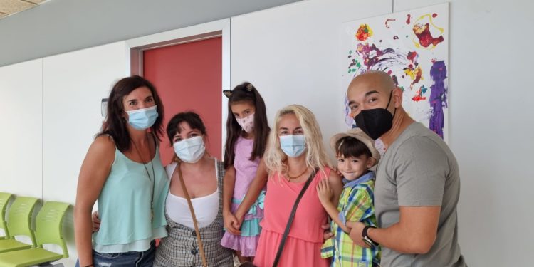 Abril Fajardo, de ocho años, con su familia posa ante uno de sus cuadros en el Centro de Salud de Sant Antoni.