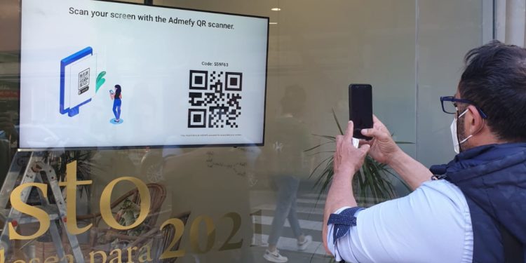 Un usuario lee un QR en una pantalla gestionada por Admefy.