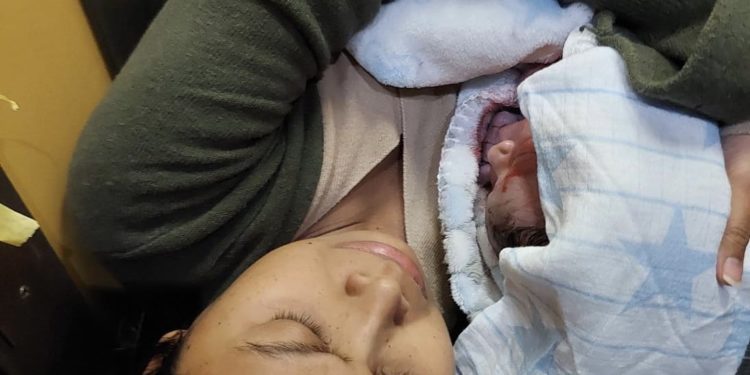 La madre y el pequeño Lian recién nacido y envuelto en una mantita en el ascesor de la vivienda. Foto Vicent M. Yern