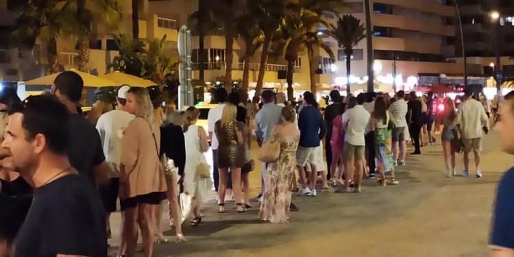 Larga cola de turistas esperando un taxi en el puerto de Ibiza