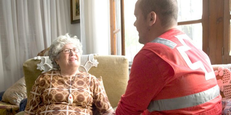 Imagen de una usuaria del servicio de 'Teleasistencia' de Cruz Roja con un trabajador de la entidad. Cedida por Cruz Roja.