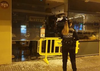 La Policía Local de Ibiza en la puerta del local con una valla para proteger la puerta completamente reventada. Foto Noudiari