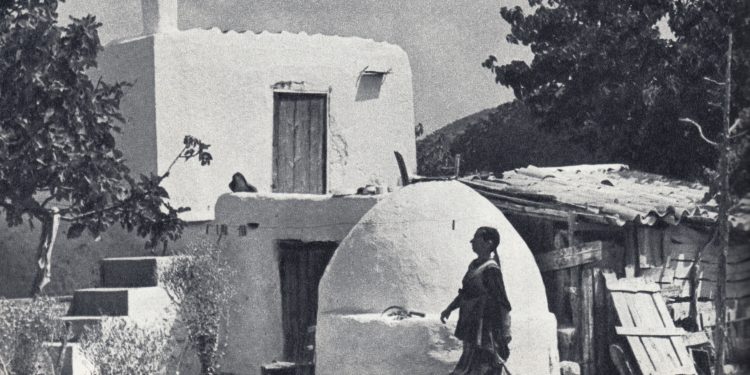 El peu de foto original diu: "Instantània de l'interior de l'illa: la dona pagesa a la seua propietat acabada d'emblanquinar". Foto: Georges Viollon