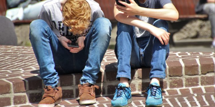 Unos menores mirando sus móviles. Foto Pexels