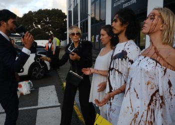 Personajes caracterizados como 'ricos' lanzan un líquido negro que simula petróleo sobre unos personajes de blanco que representan Ibiza.