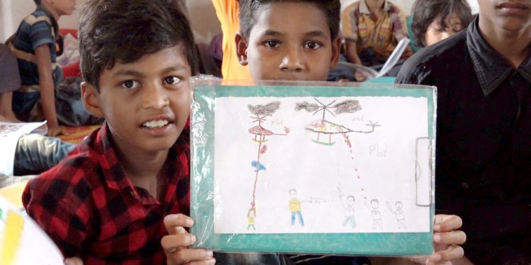 Unos niños muestran un dibujo de lo que han vivido. Pauxa Films
