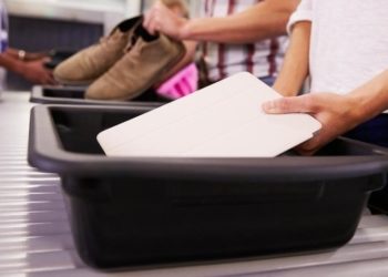 Una persona deposita un dispositivo electrónico separado en una bandeja.