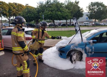 Los bomberos del parque insular de Ibiza sofocando esta mañana el incendio en el motor del coche aparcado. Foto Bombers d'Eivissa