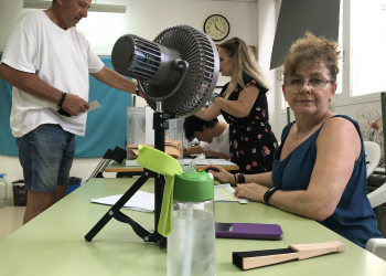 Ventilador de casa, agua fresca, abanico y pañuelos en una de las mesas electorales donde más calor hace hoy, ubicada en el CEIP Cervantes.