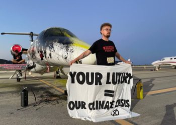 Bilbo Bassaterra despliega una pancarta junto al jet que han rociado de pintura en el aeropuerto de Ibiza. FOTO: Futuro Vegetal