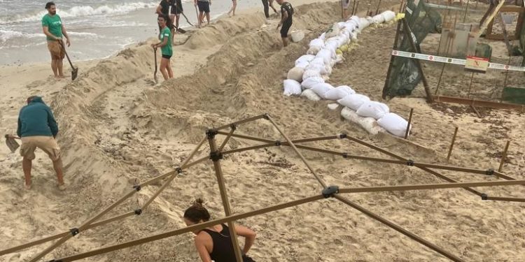 Línea de contención creada con sacos de arena y  tablones para evitar el oleaje. Fotos: Govern balear