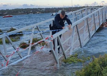 Un Policía Local recoloca el precinto a la pasarela, que quedó gravemente dañada por el temporal. Fotos Consell de Formentera