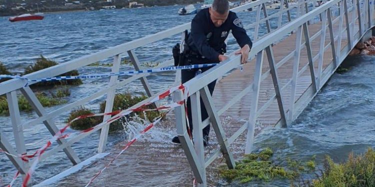 Un Policía Local recoloca el precinto a la pasarela, que quedó gravemente dañada por el temporal. Fotos Consell de Formentera