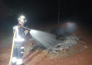 Un bombero apaga una quema de rastrojos mal apagada que amenazaba incendio anoche en Sant Joan. Fotos Bomberos