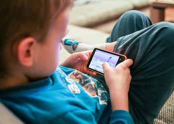 Un niño juega con un dispositivo móvil.