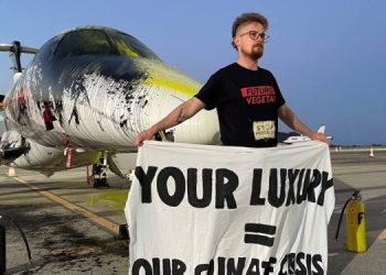 Bilbo Bassaterra sostiene una pancarta tras pintar un jet privado en el aeropuerto de Ibiza.