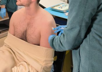 Una enfermera administra una dosis de vacuna a un paciente.