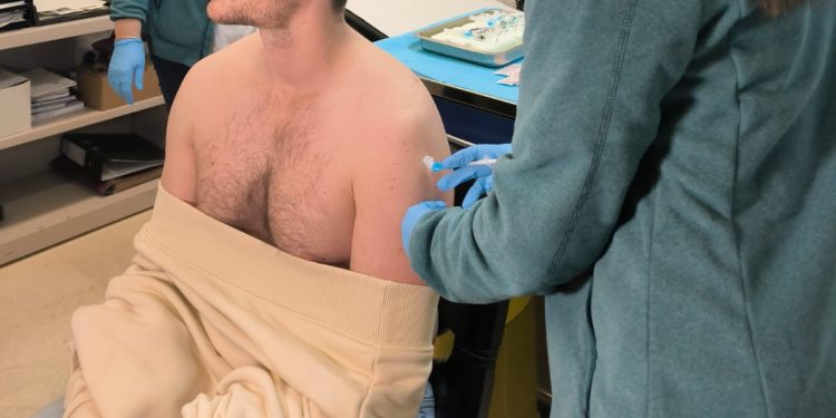 Una enfermera administra una dosis de vacuna a un paciente.