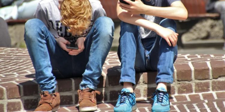 Unos menores mirando sus móviles. Foto: Pexels