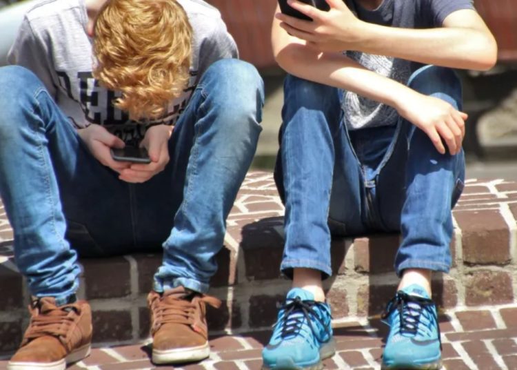 Menores mirando sus móviles. Foto: Pexels