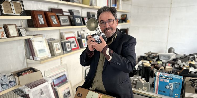 Rafa Domínguez, con una de las cámaras que usaba su padre para retratar bodas, rodeado de cámaras y material que estos días empaqueta de cara al cierre de Raymar. Foto L. F. A.