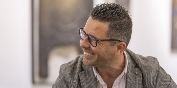 Rafael Triguero, en un gesto durante la entrevista en el antiguo Ayuntamiento de Ibiza. De fondo, un cuatro de Adrián Cardona. Fotografía de Paco Natera