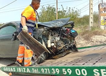 Los operarios de Grúas Ibiza retiran los restos esparcidos del coche, que ha quedado con el frontal completamente destrozado.