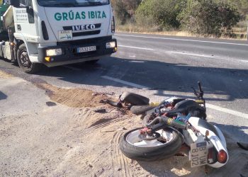 La moto derribada en la carretera junto a un vehículos de Grúas Ibiza.