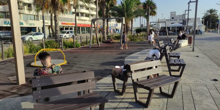 Tres personas dormitan en los bancos junto a un parque infantil de Ibiza, junto a la Estación Marítima de Formentera.