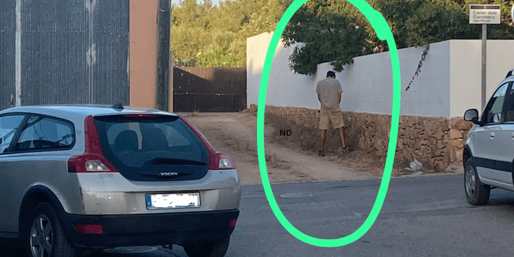 Una persona orina en la calle.