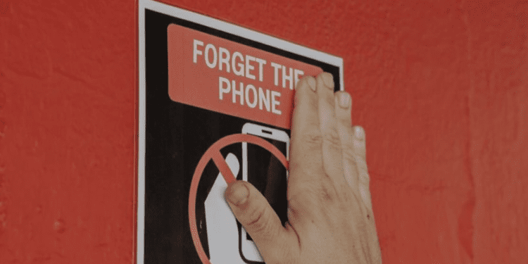 Colocando uno de los carteles que indicaban que no era posible usar móviles. Michael Bibi