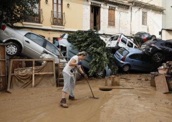 Una vecina de Paiporta limpia el lodo de una calle afectada.  EFE / Biel Aliño