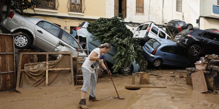Una vecina de Paiporta limpia el lodo de una calle afectada. EFE / Biel Aliño