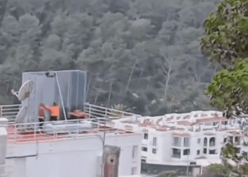 Operarios instalando la caseta metálica sobre el tejado, que no cuenta con permisos. Imagen Noudiari