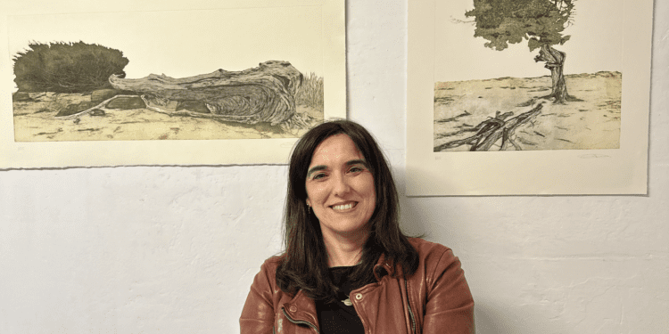 Eva Esteban posa junto a dos de los grabados  de sabinas de Ibiza de la exposición 'Resistència' de La Taller - Erredakzioa. Foto L. F. A.