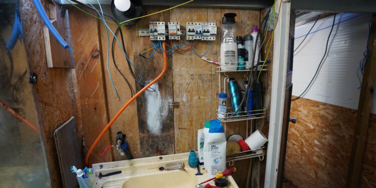 Una de las imágenes aportadas por el Ayuntamiento, en la que se un cuadro eléctrico precario en una pared de plancha de madera en una infravivienda de Can Rova, junto a tubos de bombonas y un grifo.