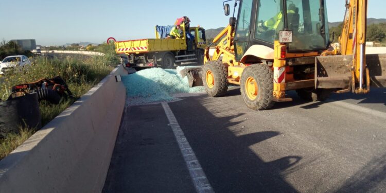 Operarios de Xarxa Viaria retiran una montaña de cristales rotos que ha dejado el camión.
