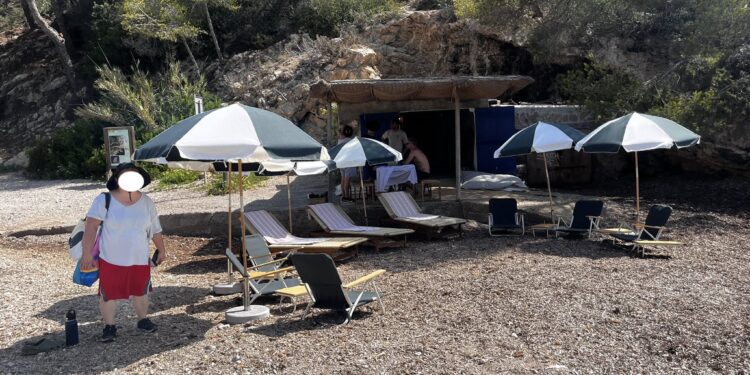 El conjunto de hamacas y sombrillas instalado en la playa por la trabajadora que se ve a la izquierda de la imagen y que al parecer las traía desde una villa privada. Fotos Joana Tur cedidas a Noudiari.es