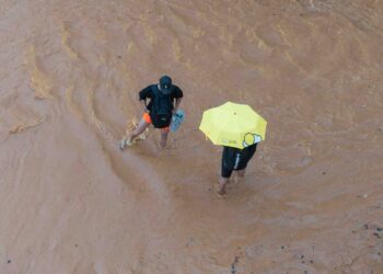 Dos personas en mitad de la corriente de agua y barro en la ciudad de Ibiza. Fotos Noudiari.es