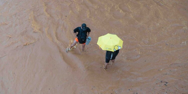 Dos personas en mitad de la corriente de agua y barro en la ciudad de Ibiza. Fotos Noudiari.es