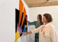 La concejala Carmen Domínguez y la comisaria de la muestra, junto a una de las obras que se expondrán. / AE