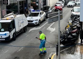 Un empleado de Valoriza, tras aplicar agua a presión. Junto al camión, la Policía Local de Ibiza que acudió al aviso de un vecino. Fotos Noudiari.es