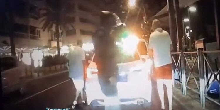 A la derecha, con pantalón rojo, el turista al entrar en el taxi. En el centro de la imagen, de oscuro, el ladrón que espera su momento. / Exponiendo Ibiza