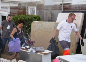 Voluntarios ayudando a vecinos a sacar a la calle enseres afectados por las lluvias.
