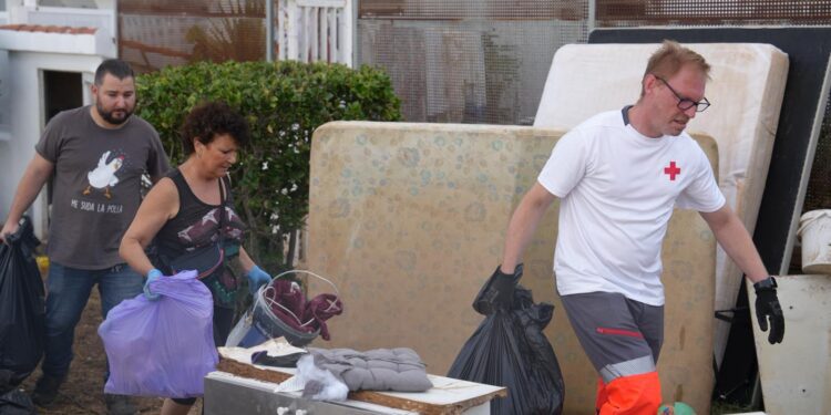 Voluntarios ayudando a vecinos a sacar a la calle enseres afectados por las lluvias.