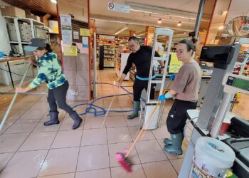 Trabajadores limpiando de barro el interior de un comercio en es Pratet. / D.V.