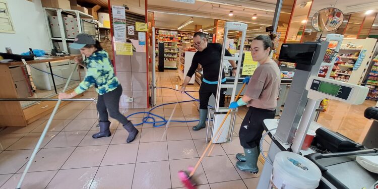 Trabajadores limpiando de barro el interior de un comercio en es Pratet. / D.V.
