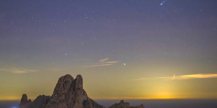 Clicka sobre la imagen de Paco Natera para verla al completo. El fotógrafo ha captado al cometa Lemmon (C/2025 A6) surcando el cielo estrellado sobre Es Vedrà, como se aprecia en la derecha de la imagen. Fotografía Paco Natera.