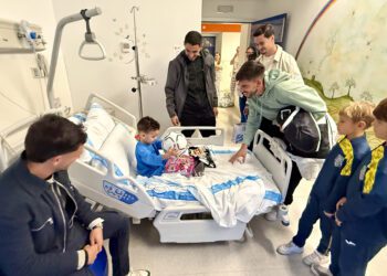 Los jugadores de la Penya ofrecen unos detalles a uno de los niños ingresados. / SCR Penya Deportiva